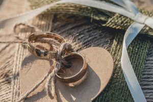 A closeup shot of golden wedding rings attached to a brown heart-shaped textile